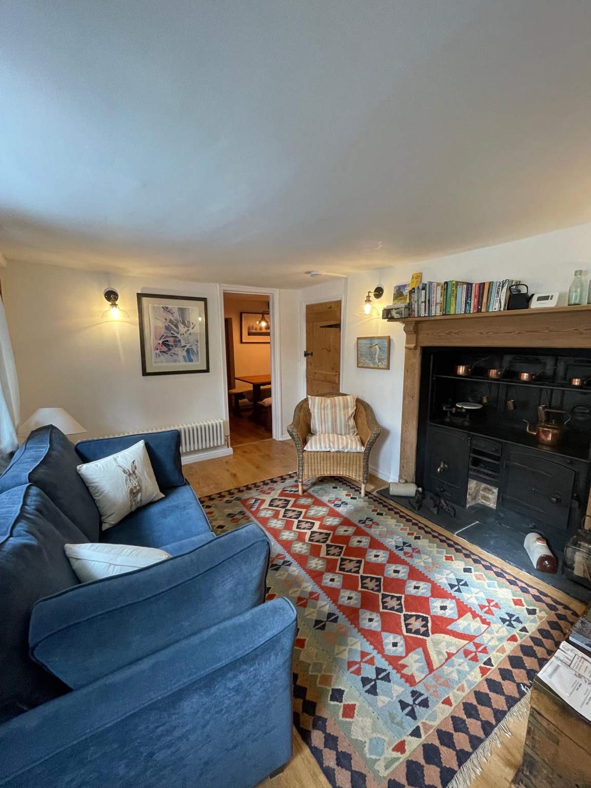 Refurbished sitting room with blue sofa, patterned rug and original range
