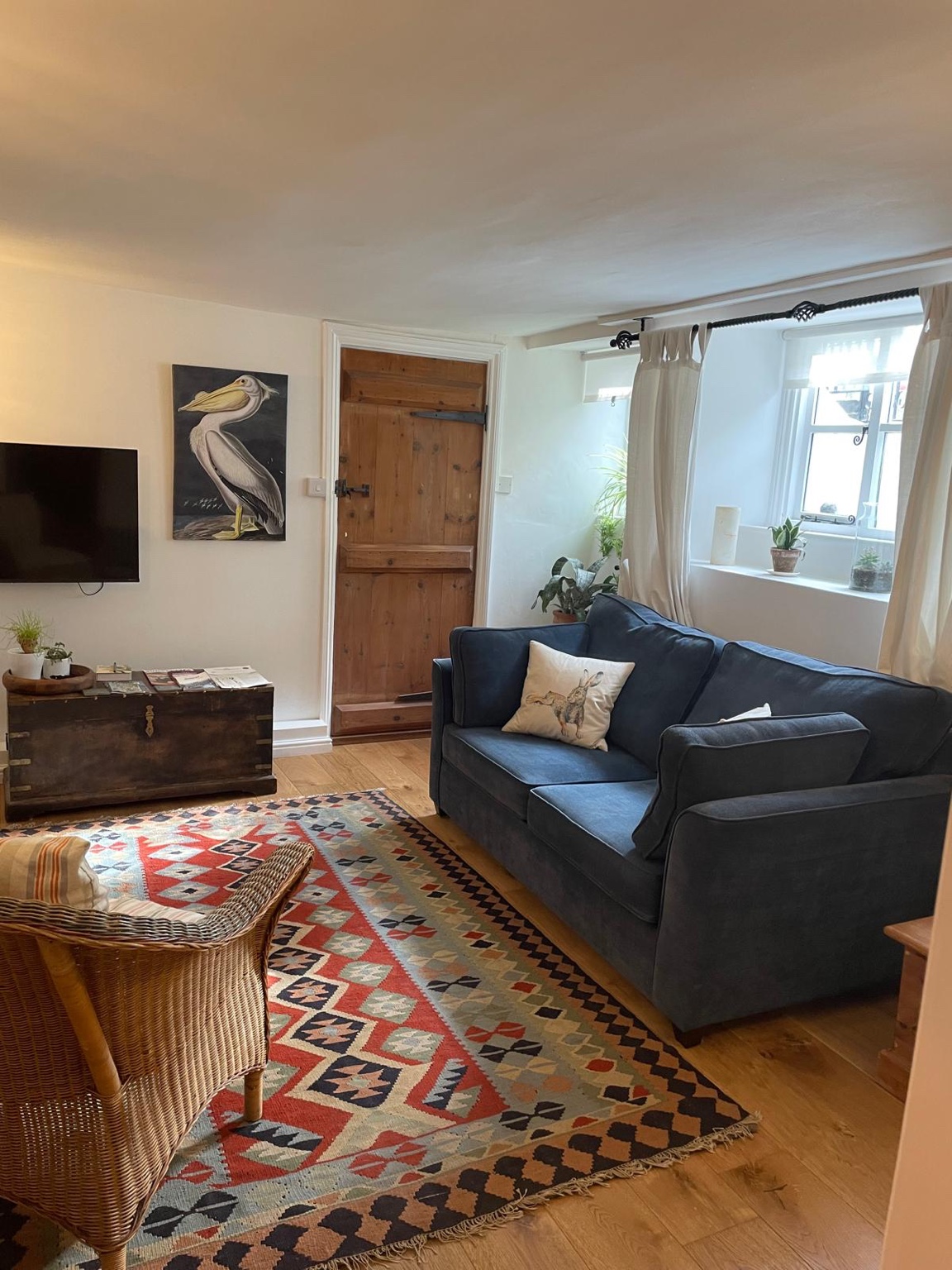 Refurbished sitting room with blue sofa, television and window